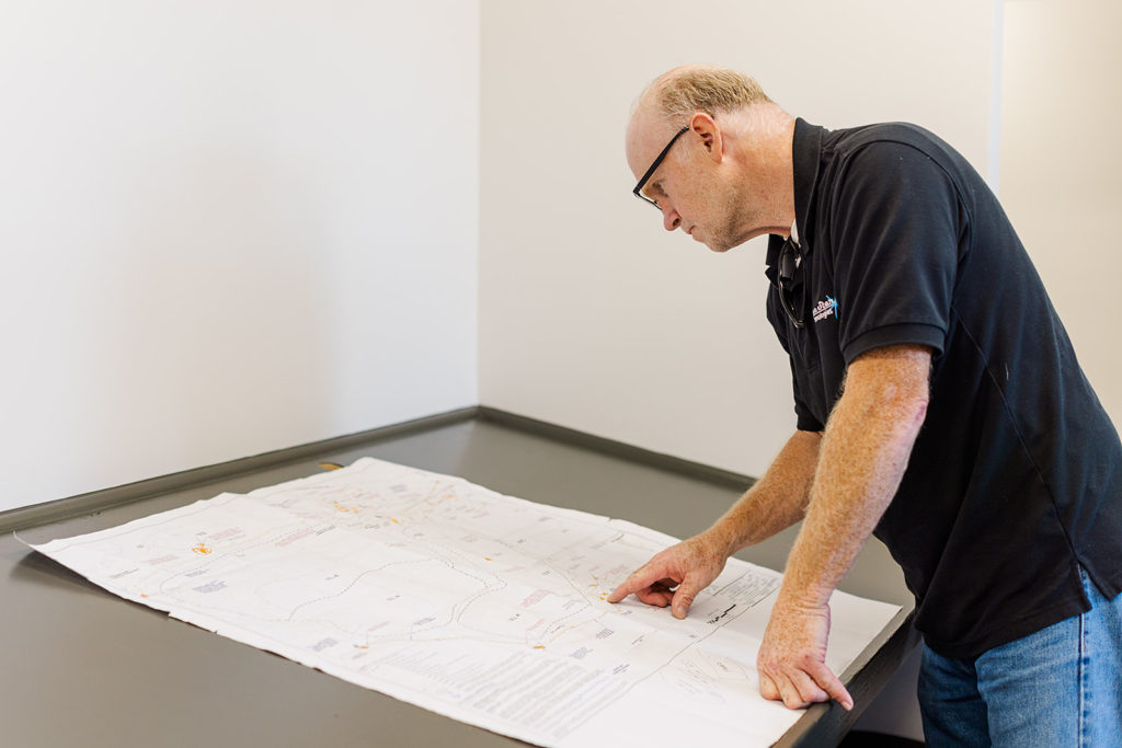 A man reviews a paper schematic while standing