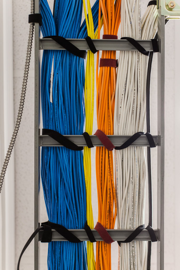 Bundles of colored cables run along a wall