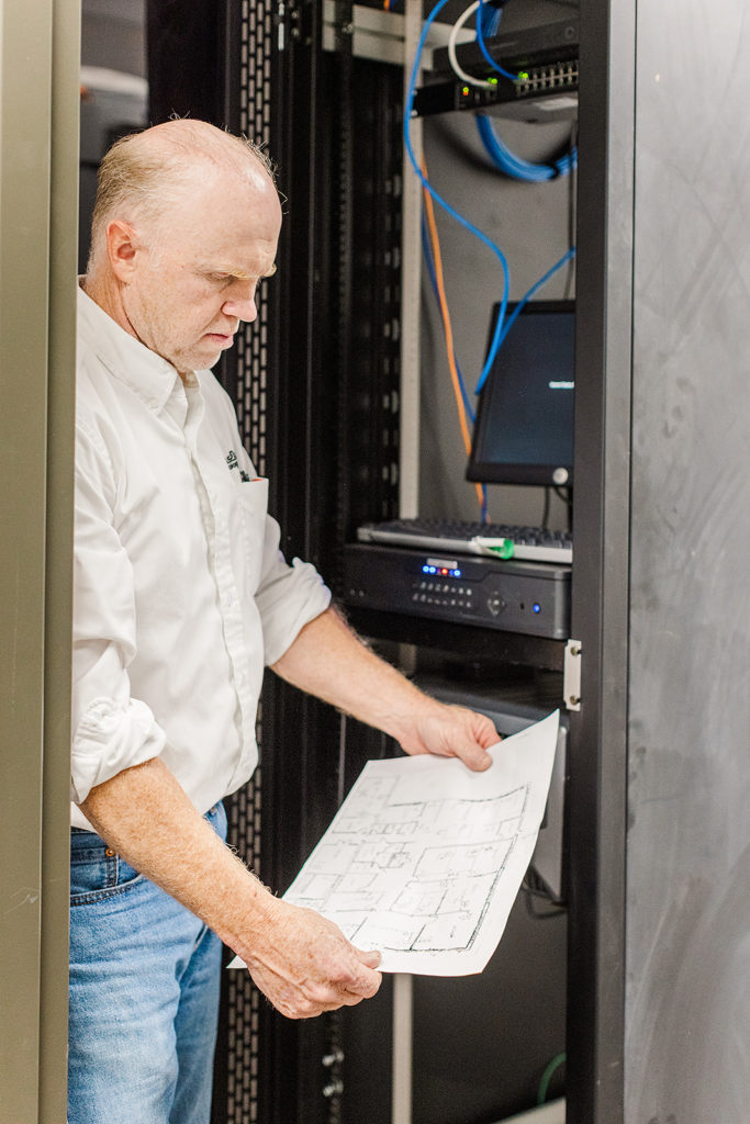 A man stands next to a server rack