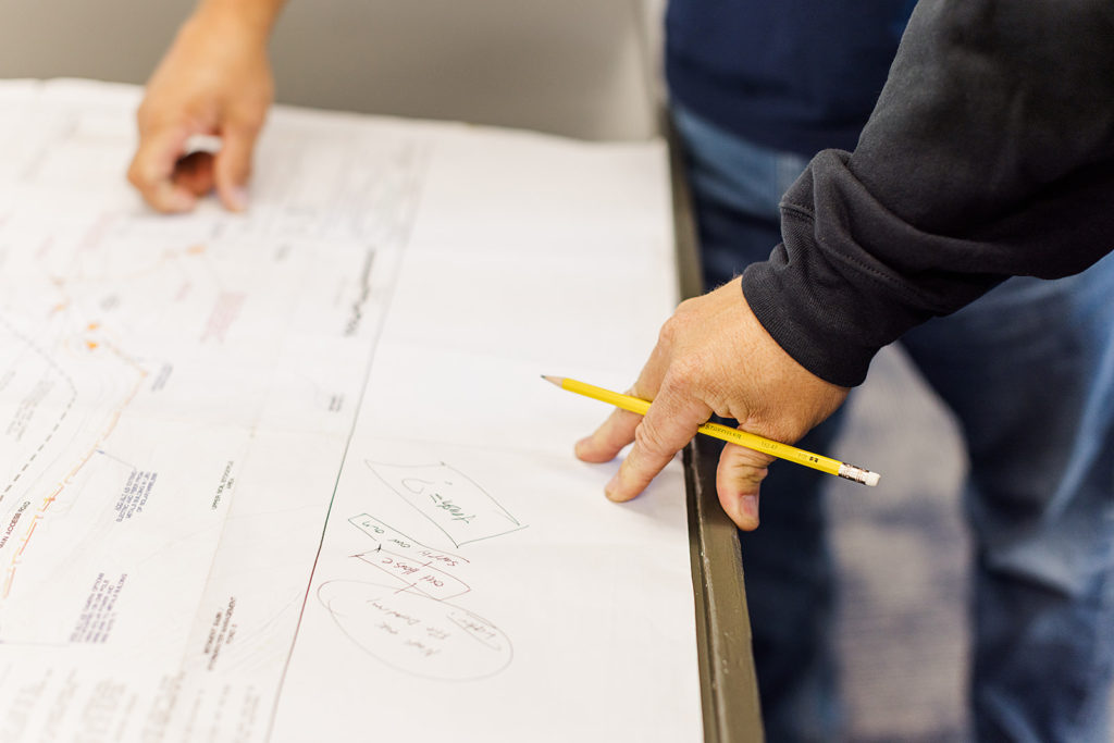 Someone reviews a paper schematic while holding a pencil