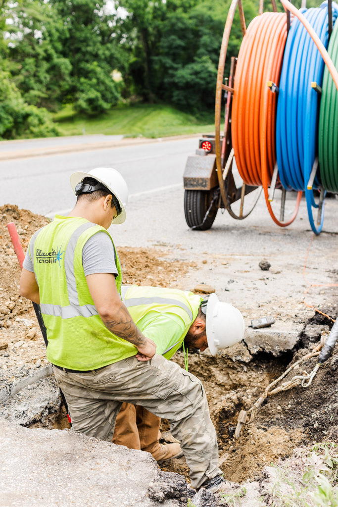 Workers install colored cables in a trench